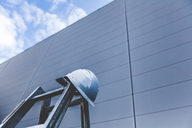 working man´s helmet on ladder in front of a huge wall. high goals for success.